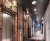 W hotelu sieci Moxy (zdjęcie po lewej) na warszawskiej Pradze sufit zdobią ciemne panele współgrające  z szarą wykładziną.