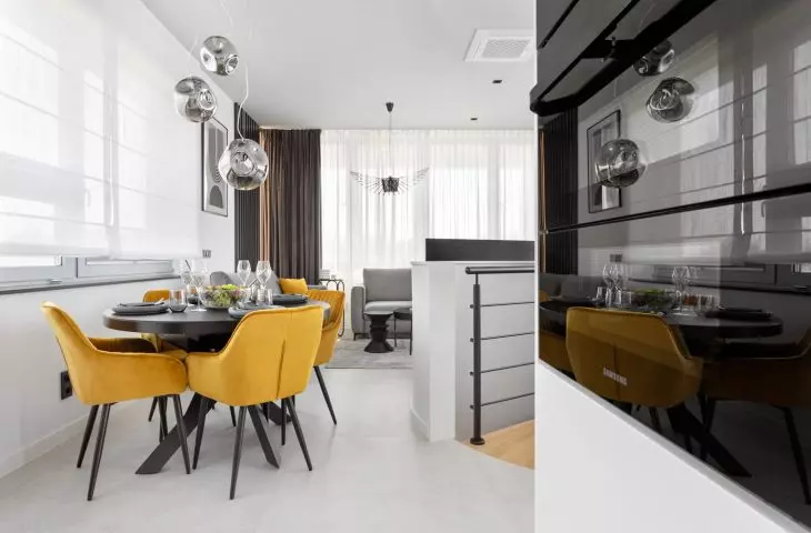 Interior of an apartment in the Baildomb estate in Katowice - dining room with a black table and yellow upholstered chairs