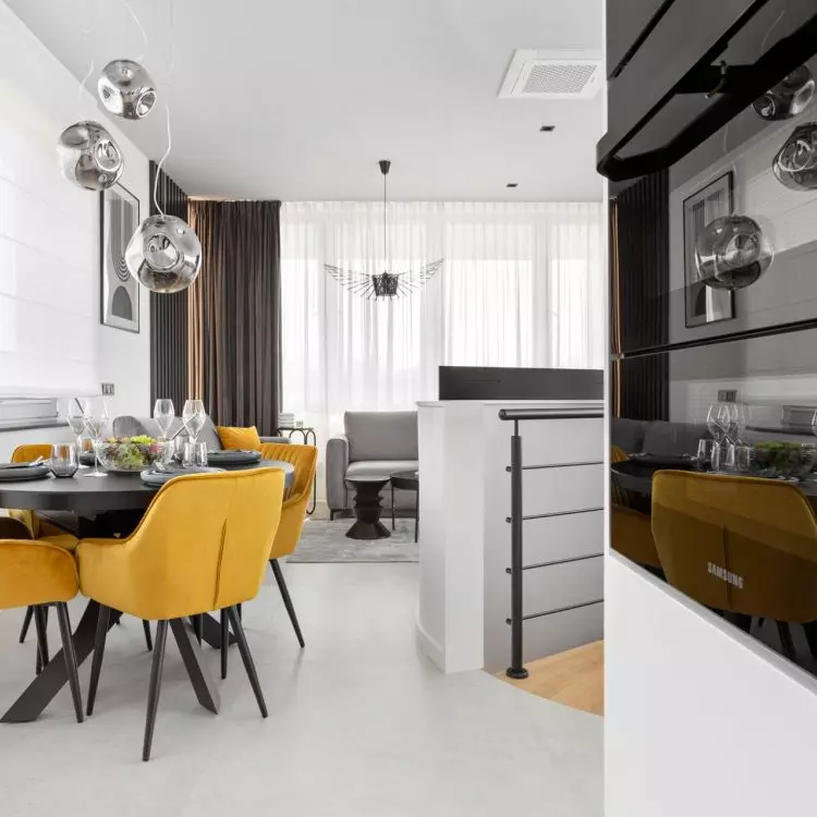 Interior of an apartment in the Baildomb estate in Katowice - dining room with a black table and yellow upholstered chairs