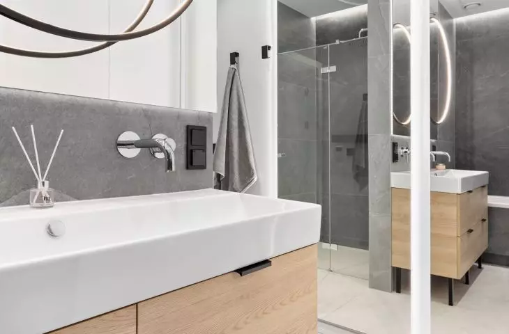 The interior of an apartment in the Baildomb estate in Katowice - a bathroom with gray tiles and a large sink with two faucets