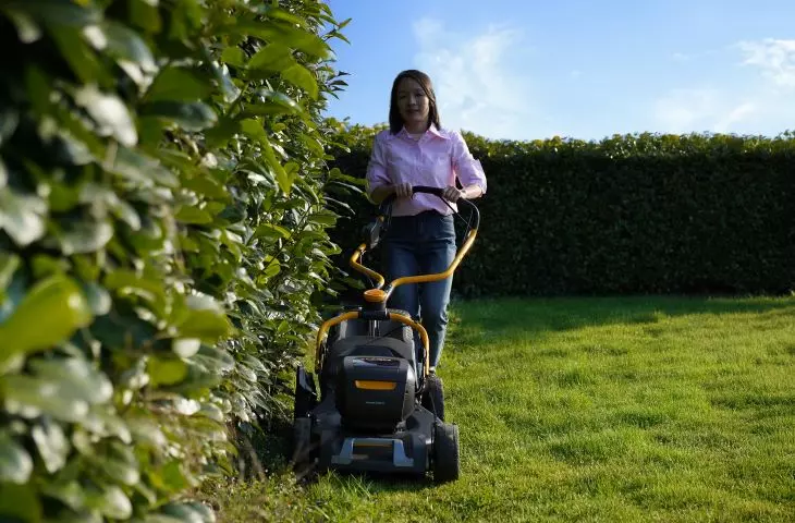 Cordless lawnmower on the background of a neat lawn, presenting mobility and convenience of use