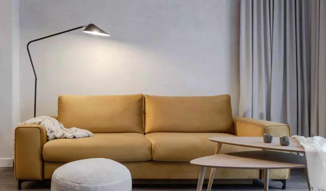 Musztardowa sofa stanowi barwny akcent w salonie