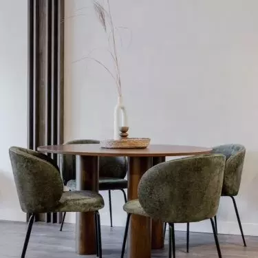The round wooden table is surrounded by upholstered chairs in a shade of deep green