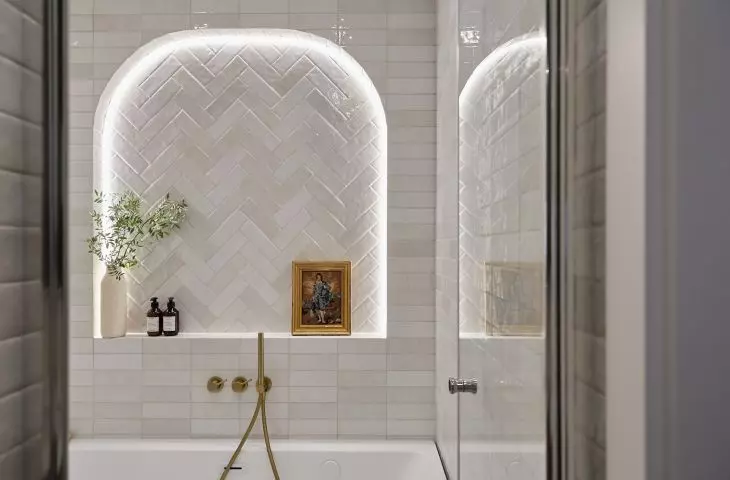 The bathing area in the bathroom is located behind a glass door 