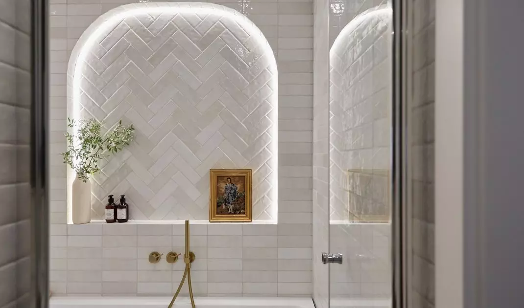 The bathing area in the bathroom is located behind a glass door 