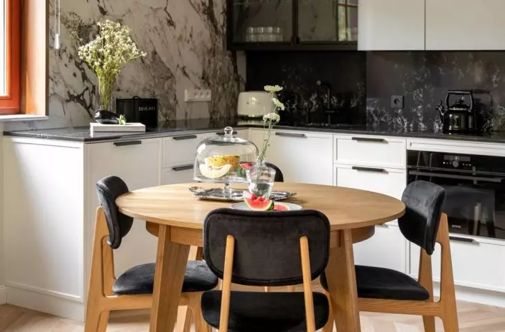 Wooden round table is complemented by black upholstered chairs
