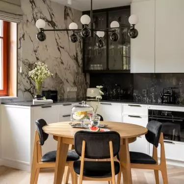 Wooden round table is complemented by black upholstered chairs