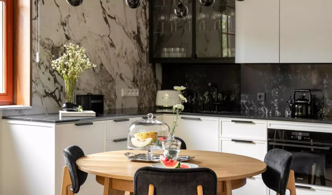 Wooden round table is complemented by black upholstered chairs
