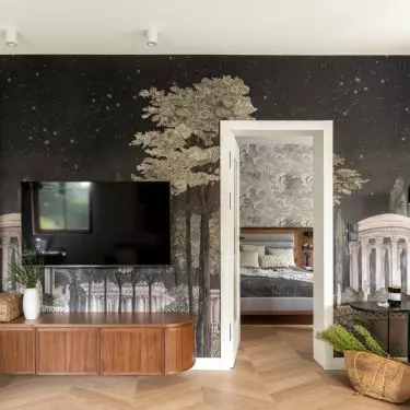 The wall in the living area has been decorated with wallpaper with a night city motif