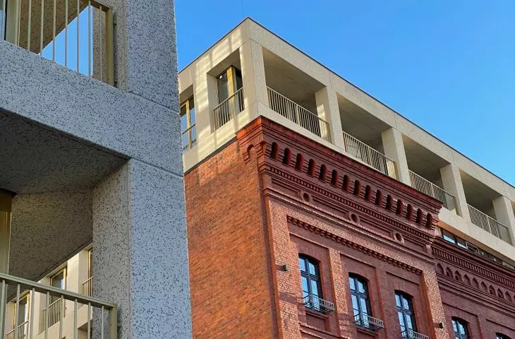 z ceglanym fragmentem szkoły wciągniętym w kubaturę jednego z budynków kontrastuje rytmiczna struktura betonowej kraty