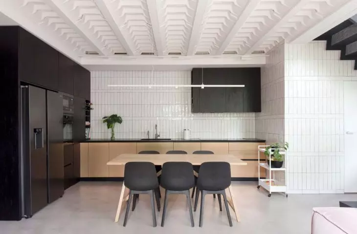 The kitchenette is decorated in a contrasting black and white color scheme, which is warmed by wooden elements