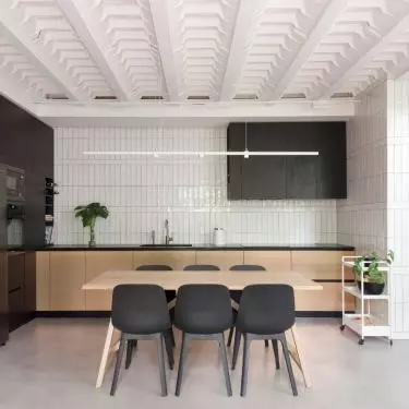 The kitchenette is decorated in a contrasting black and white color scheme, which is warmed by wooden elements