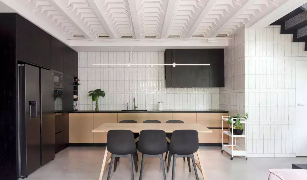 The kitchenette is decorated in a contrasting black and white color scheme, which is warmed by wooden elements