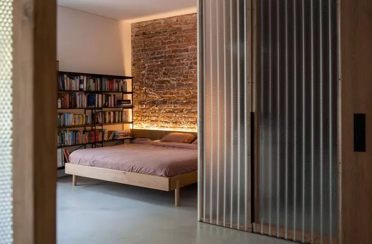 The wall behind the bed in the bedroom is covered with brick