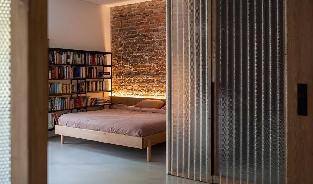 The wall behind the bed in the bedroom is covered with brick