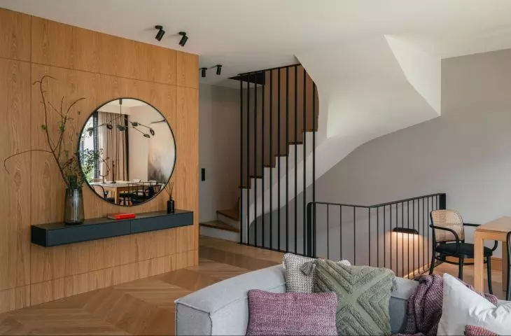 Entrance area with a round mirror hung against a veneered wall