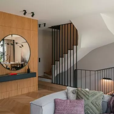 Entrance area with a round mirror hung against a veneered wall