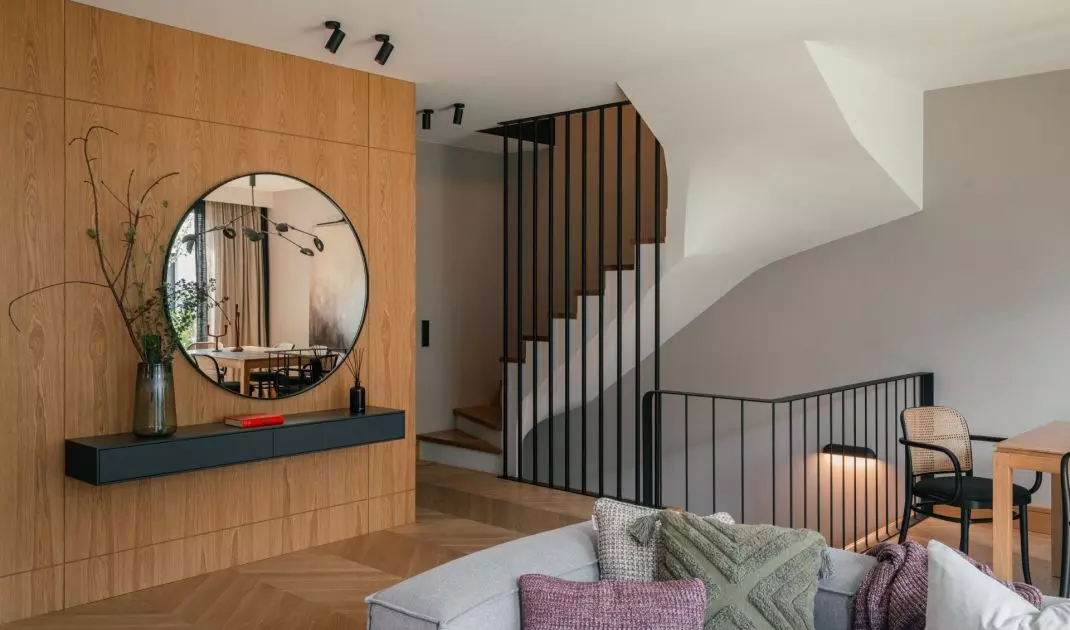 Entrance area with a round mirror hung against a veneered wall