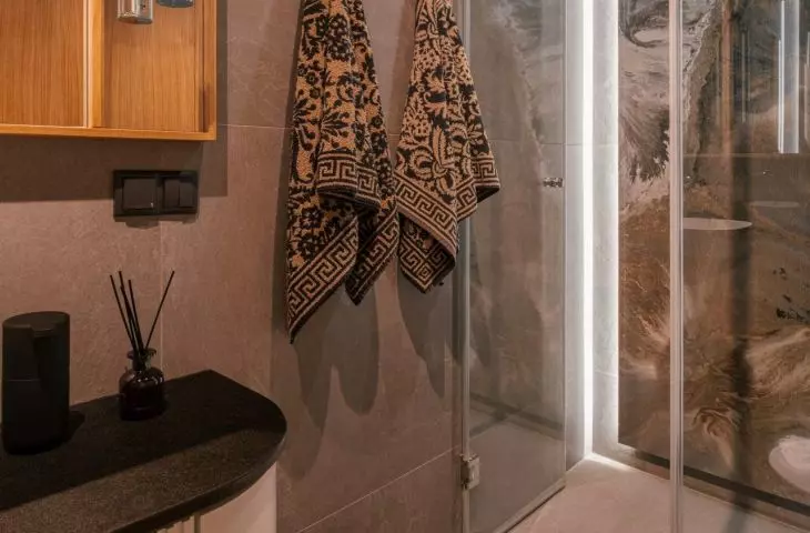 The wall of the shower is decorated with an expressive tile with a graphic drawing
