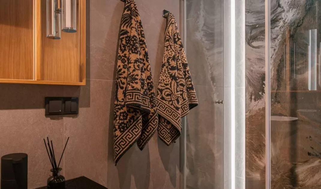 The wall of the shower is decorated with an expressive tile with a graphic drawing