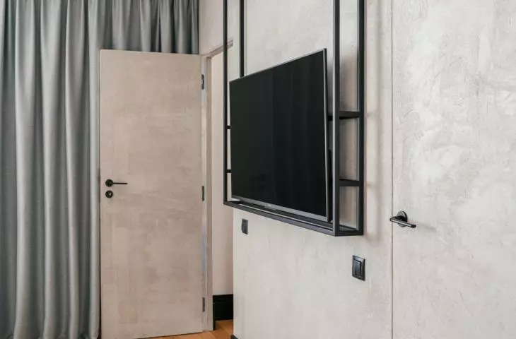 Opposite the bed, a black metal structure with a TV was installed