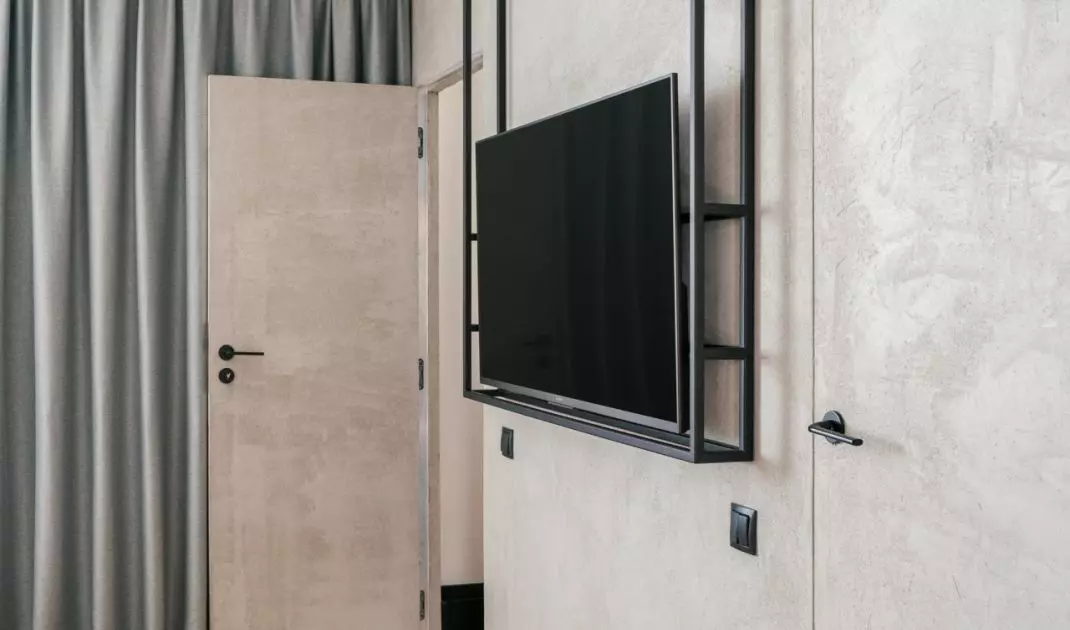 Opposite the bed, a black metal structure with a TV was installed