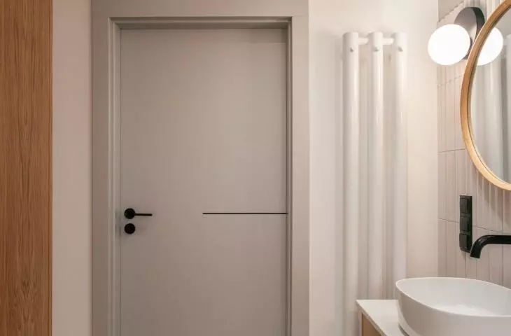 Grey door and white radiator complete the arrangement of the lighter bathroom