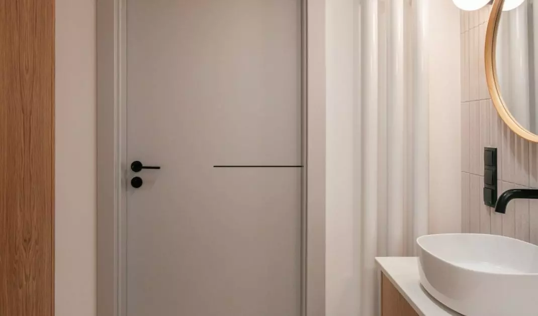Grey door and white radiator complete the arrangement of the lighter bathroom
