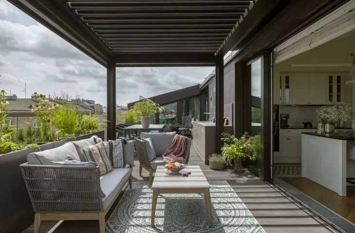 The terrace, surrounded by greenery and plants in pots, is an extension of the living room