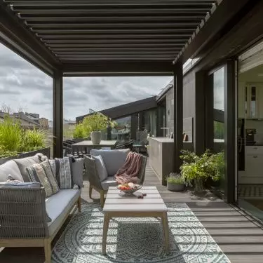 The terrace, surrounded by greenery and plants in pots, is an extension of the living room