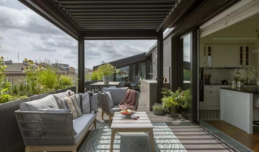 The terrace, surrounded by greenery and plants in pots, is an extension of the living room