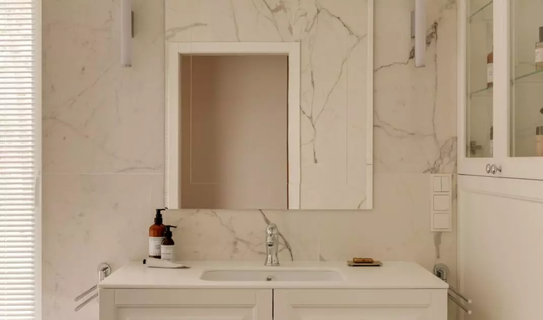 The walls of the bathroom are covered with tiles with a natural stone motif