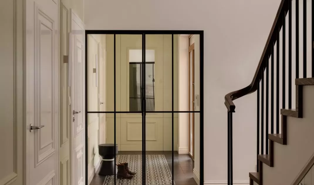 The hallway is separated from the other rooms by a glass door in a black metal frame 