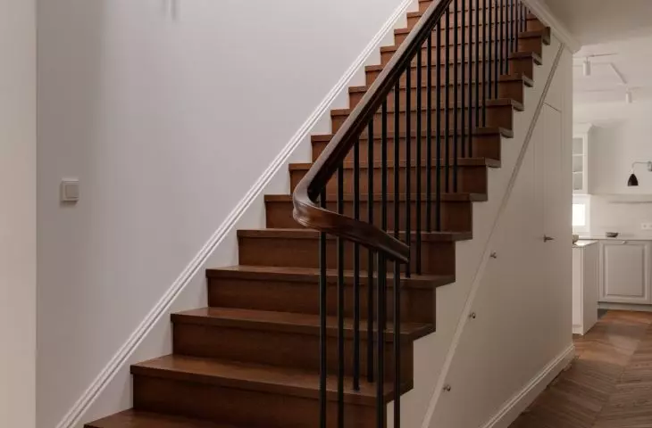 A carpeted staircase, clad with natural oak paneling in a dark shade, leads to the First Floor