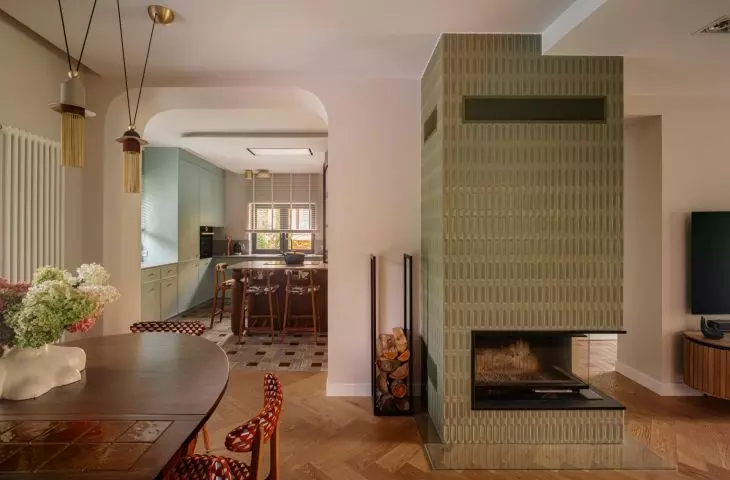 The centerpiece of the living room is a fireplace finished with glossy vertical tiles in a shade of olive green