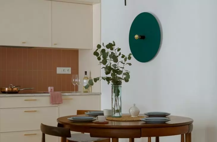 The heart of the kitchen is a round wooden table surrounded by four chairs with gray upholstered seats