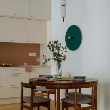 The heart of the kitchen is a round wooden table surrounded by four chairs with gray upholstered seats