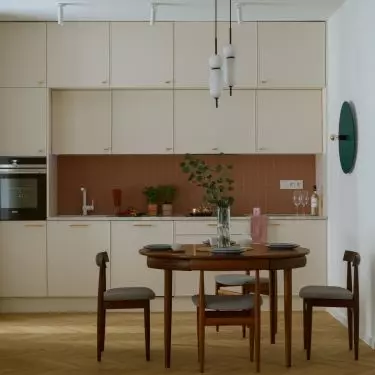 The kitchen combines light-colored cabinets with brick tiles to create a contrast 