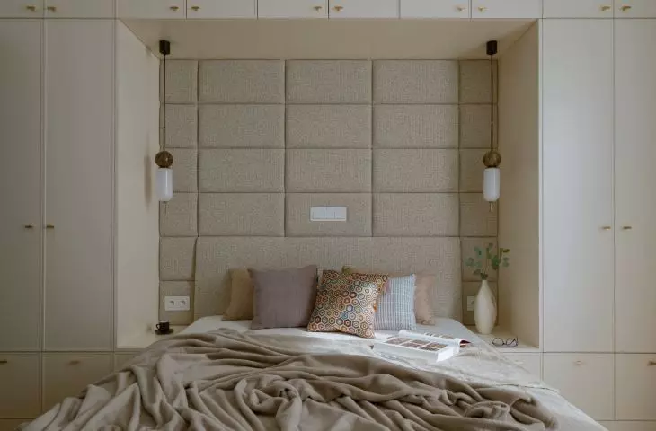 The focal point of the bedroom is a bed with a high, upholstered headrest