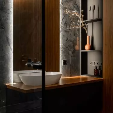 Bathroom harmoniously combines black marble with dark wood 