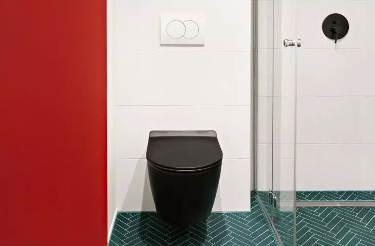 The white built-over toilet has been fitted with round red handles