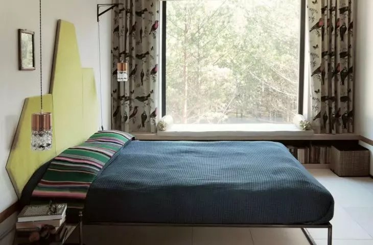 Bedroom with a bed equipped with a green headrest with an interesting form