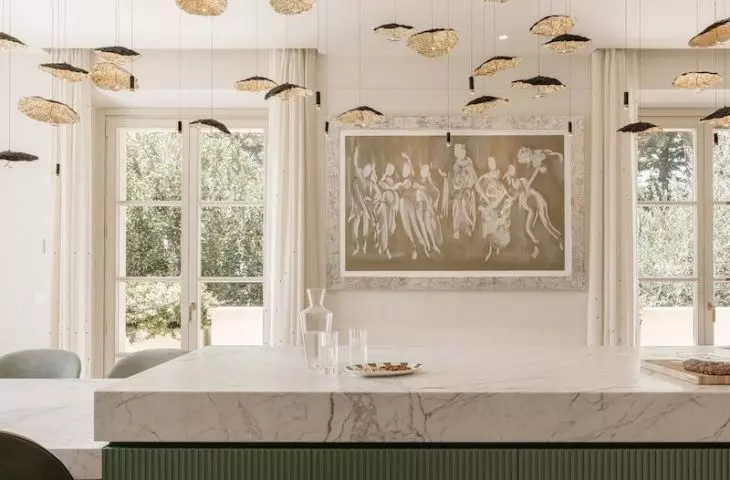 A striking gold lamp hangs above the pistachio shade island
