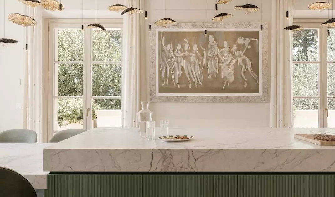 A striking gold lamp hangs above the pistachio shade island