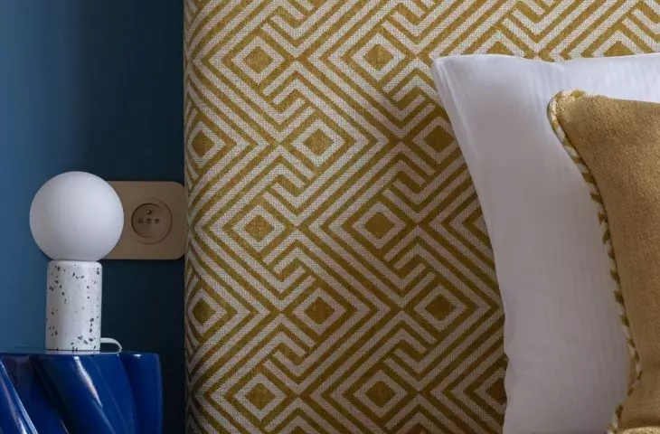 The upholstered headrest of the bed is decorated with a design reminiscent of the 1960s.