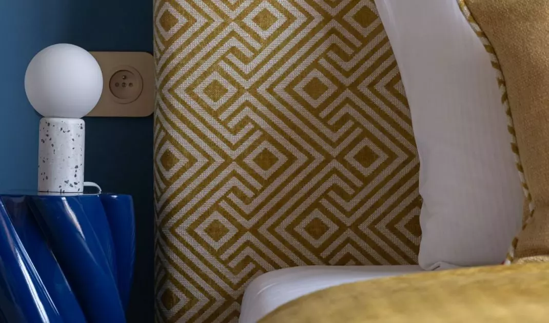 The upholstered headrest of the bed is decorated with a design reminiscent of the 1960s.