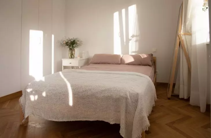 The bedroom is dominated by white, pink and wood 