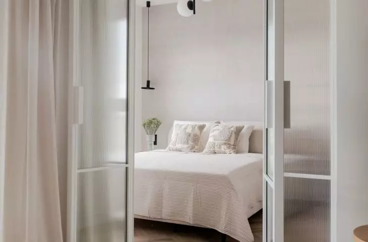 The bedroom is separated from the rest of the apartment by a glass wall