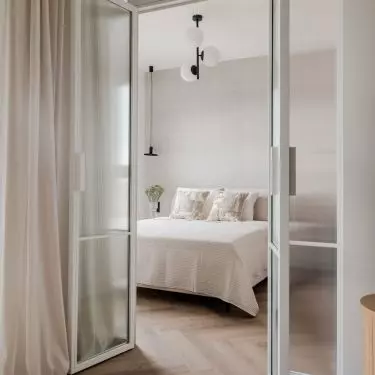 The bedroom is separated from the rest of the apartment by a glass wall