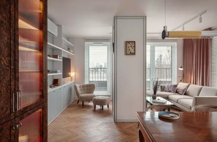 In the living room, attention is drawn to the comfortable gray sofa with colorful cushions, set by large windows with blinds that offer views of the city